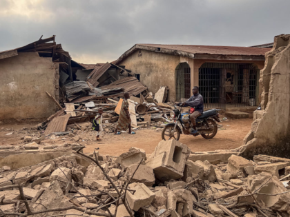 TOPSHOT - Residents and a motorcyclist move between destroyed structures in Offa on Decemb