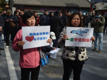 Two relatives of passengers missing on Malaysia Airlines MH370, reads hold placards during