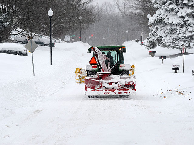 A snow removal machine makes its way along Nettle Creek Road after over two feet of heavy