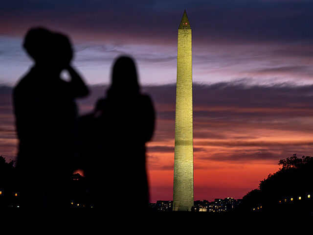 People walk past the Washington Monument at sunset on September 14. 2025 in Washington, DC