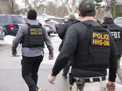 Federal agents walk through a parking lot after executing a search warrant at Ultimate Hom