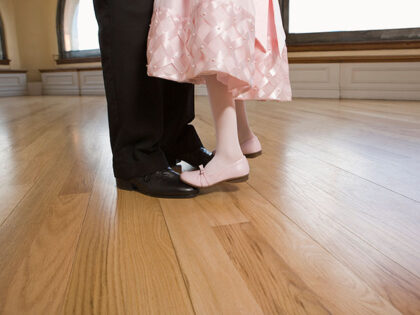 Daughter standing on feet of father dancing - stock photo