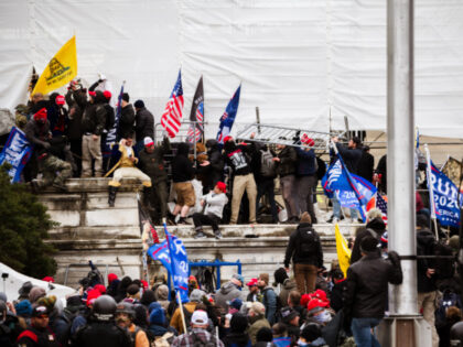 A group of pro-Trump protesters climb the walls of the Capitol Building after storming the