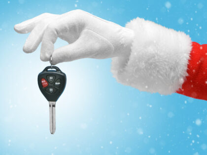 Hand in costume Santa Claus is holding car keys / studio shot of man's hand holding k