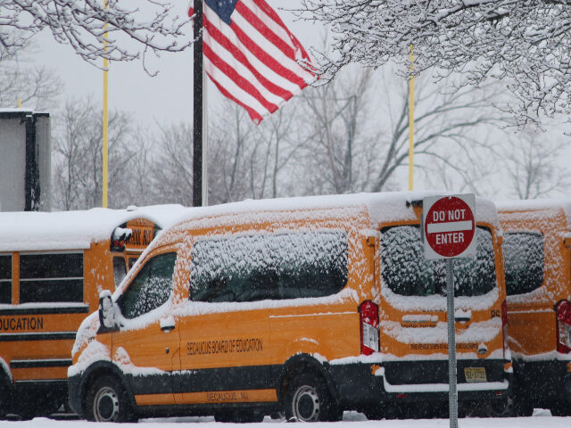 School vehicles are seen as roads are covered with snow after snowfall during winter at Hu