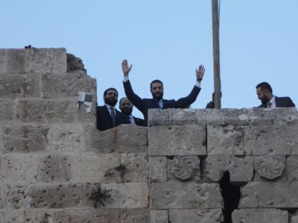 Syrian President Ahmed al-Sharaa waves to the crowd at the gate of Aleppo's Citadel d