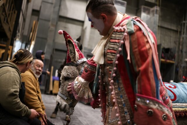 Actor Gregory Warren, who plays Parpignol, pats Wanda the donkey as they wait backstage ah