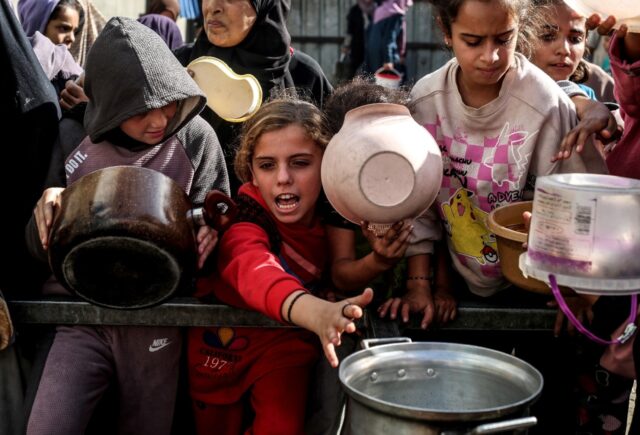 Displaced Palestinian children waited for food at a shelter in Nuseirat, Gaza, in November