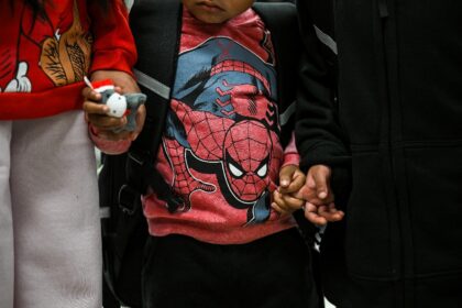 Three-year-old Franklin (C) holds hands with six-year-old Garibaldi (R) and eleven-year-ol