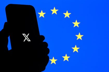 The logo of social network X is displayed on a smartphone in front a Euopean Union flag in