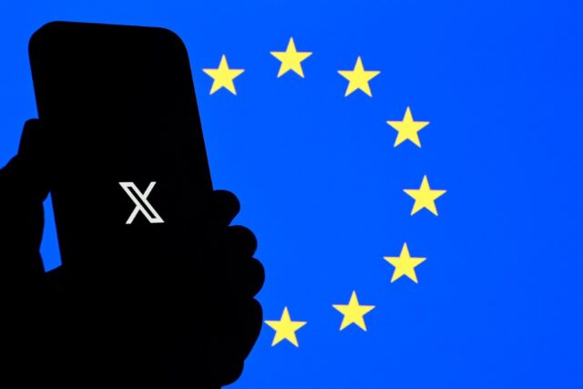 The logo of social network X is displayed on a smartphone in front a Euopean Union flag in