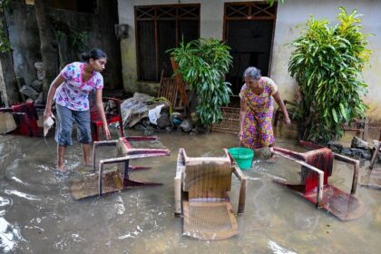 Residents salvage their belongings at an inundated house following flash floods in the aft