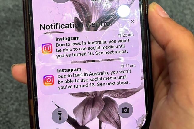 A teenager holds a mobile phone displaying a message from social media platform Instagram