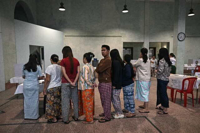Voters line up inside a polling station during the first phase of Myanmar's general e