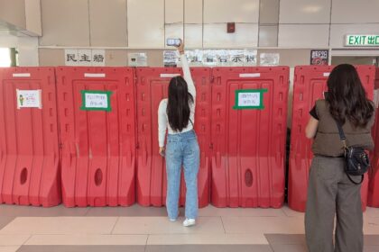 A woman takes a photo with her phone above barricades in front of the student union-run no