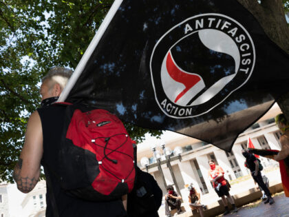 An anti-fascist protester holds a flag on the Christian Science Plaza, Saturday, July 11,