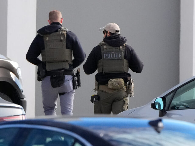 Federal agents stand outside a warehouse as federal officials tour the facility to conside