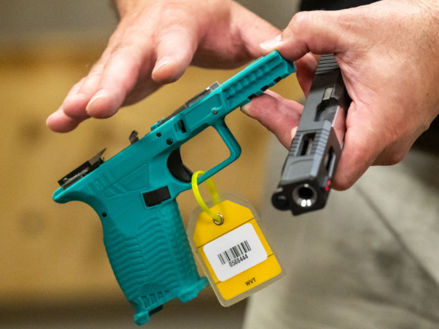 An ATF official holds a 3D printed gun in the National Firearm Reference Vault, which hold