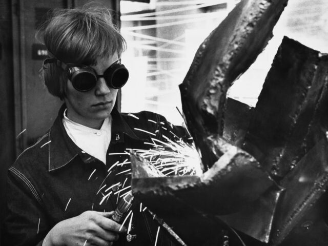 A Welder Welds A person wearing welding goggles as they use a welding torch to construct an abstract scul