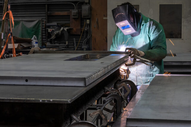 A worker arc welds a metal door during production at the Metal Manufacturing Co. facility