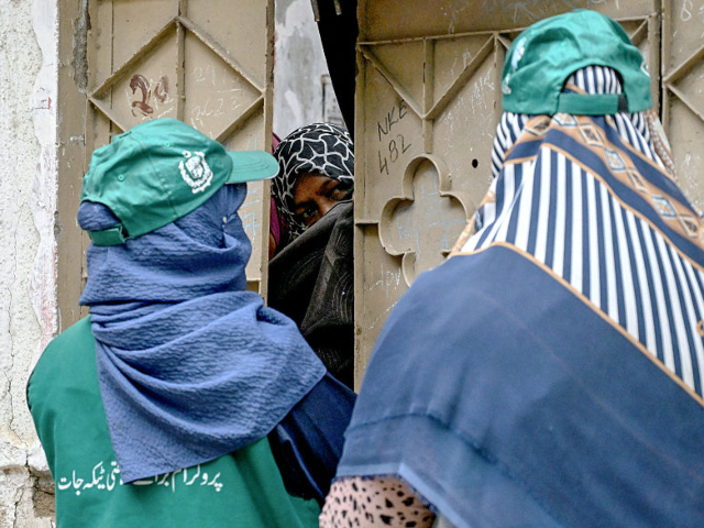 GettyImages-2236847161 Health workers speak with a woman (C) in Karachi on September 24, 2025, during a door-to-d