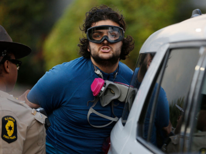 Local and state law enforcement detain a man as hundreds of protesters gather near an Immi