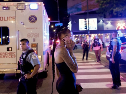 A person watches police officers work on July 3, 2025, at the scene where four people were