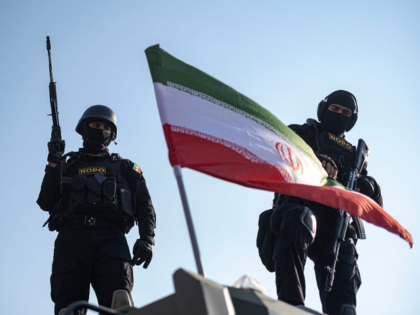 Two armed members of Iran's police special forces stand behind a country flag placed on an