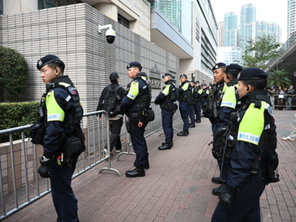 A visitor passes by police as they enter the West Kowloon Magistrates' court in Hong Kong