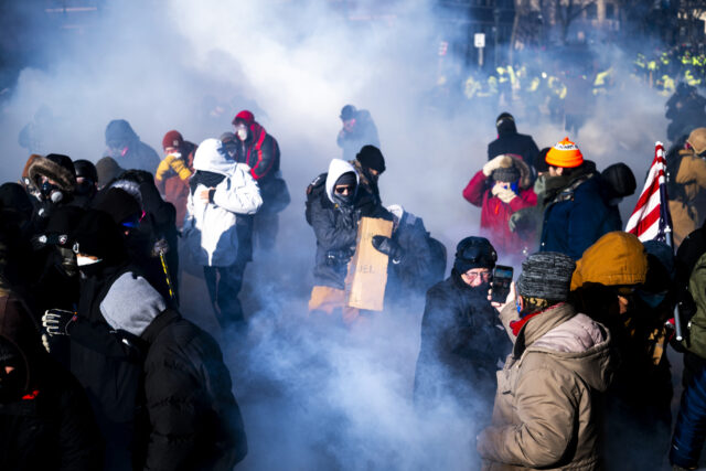MINNEAPOLIS, MINNESOTA - JANUARY 24: People run as they are enveloped by tear gas thrown b