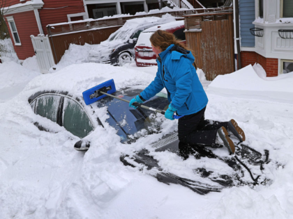 GettyImages-2257934743 BOSTON, MA - January 26: A woman uses a Snow Joe to clear the snow from her car on January