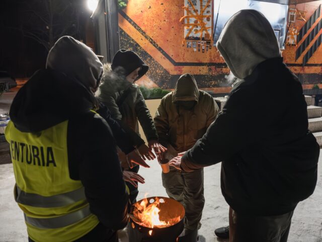 Kyiv residents receive hot meals and warm themselves by an open fire near a mobile kitchen