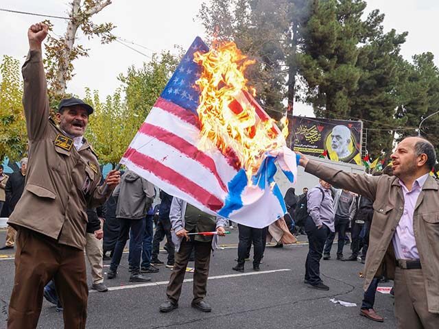 People burn a US and Israeli flag during a rally outside the former US embassy in Tehran a