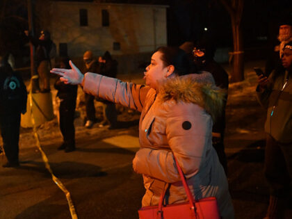 A protestor gestures towards federal law enforcement agents and police officers in riot ge