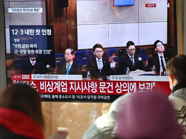 People watch a television screen showing a live broadcast of the trial verdict of South Ko