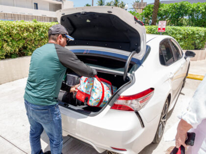 Miami Beach, Florida, Hispanic man, uber driver, loading luggage into car. (Photo by: Jeff