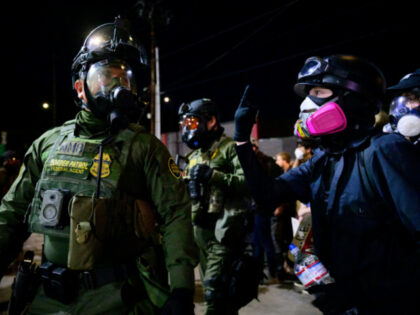 Federal agents stand guard to keep demonstrators away from an Immigration and Customs Enfo