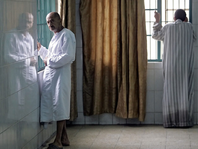 Iraqi stand near windows inside al-Rashad Asylum in Baghdad, 28 March 2006. Three years af