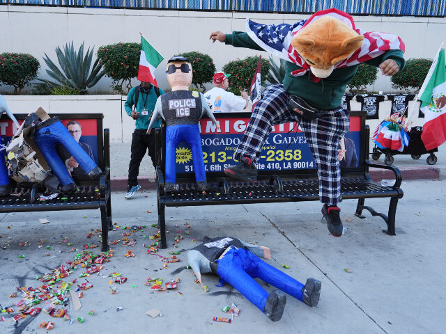A demonstrator smashes a piñata in the shape of an ICE agent during a protest to denounce