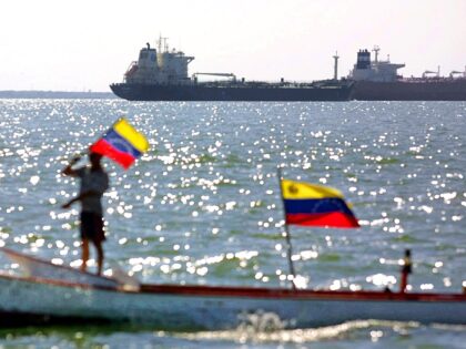 A fisher flies the Venezuelan flag on his boat in front of moored tanker Pilín León, 18