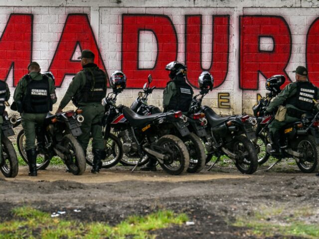 caracas gangs Members of the National Guard stand guard in front of a mural of ousted Venezuela's Presid