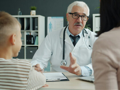 Doctor consults with mother and child in office.