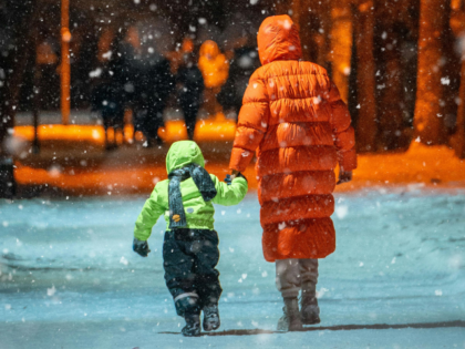 Woman with Kid Walking on Sidewalk on Winter Night
