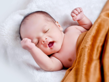 Baby Lying On White Fur With Brown Blanket