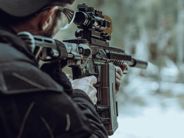Man Aiming Rifle in Outdoor Shooting Range