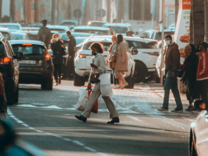 group of people walking on a city street filled with lots of traffic