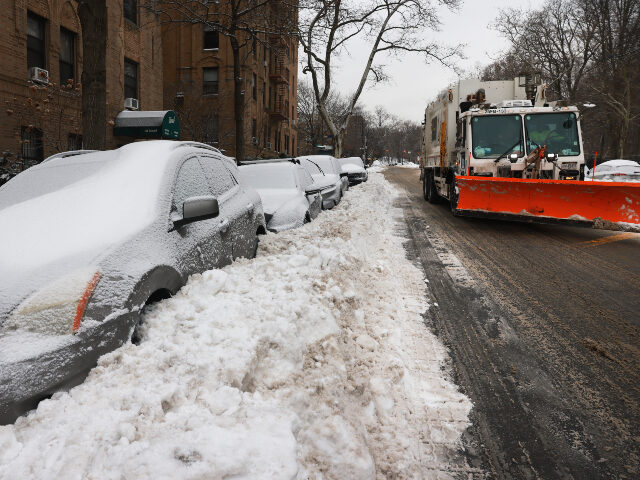 A snow plow moves along a snow-covered street in Brooklyn after a storm left nearly one fo