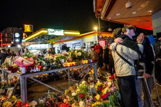 An injured survivor (R) greets a person next to a makeshift memorial near the site of the