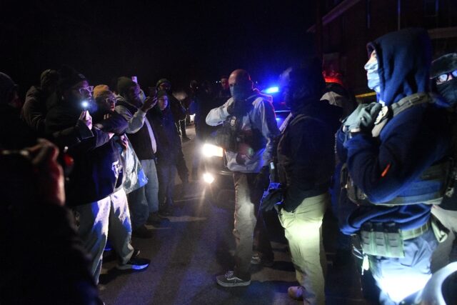 Masked ICE agents and demonstrators face off following the shooting of a Venezuelan man by