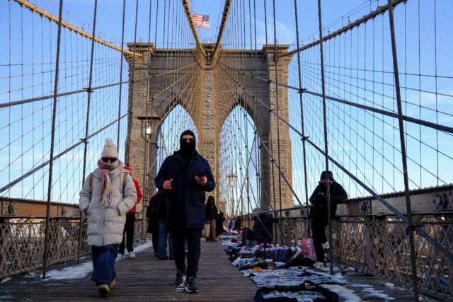 People brave the cold temperatures while walking on the Brooklyn Bridge in the Manhattan b